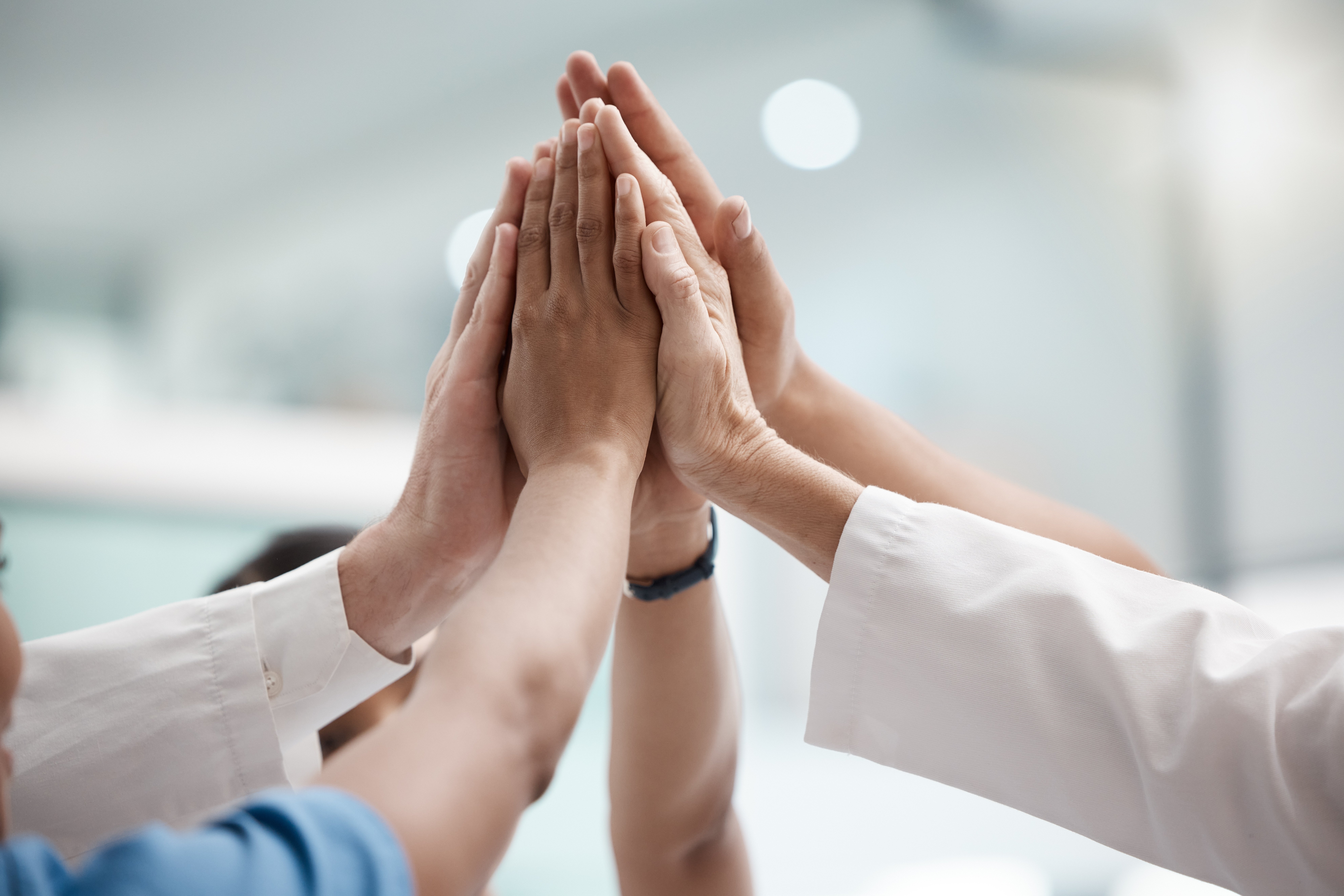 group hands clinical setting - © PeopleImages / Shutterstock